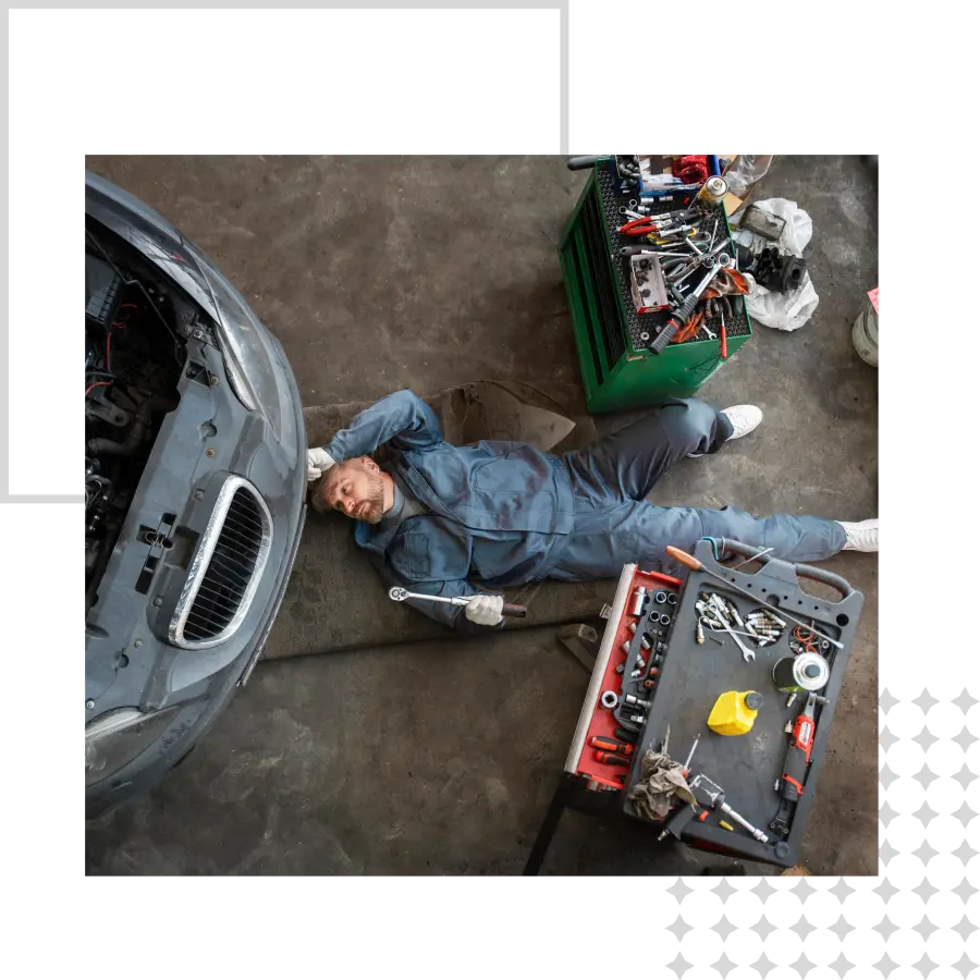 Mechanic lying beside car and tools.
