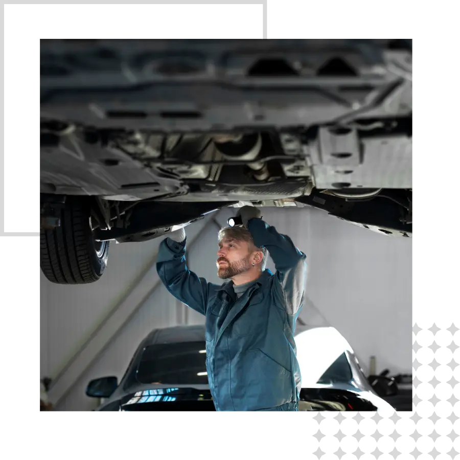 Mechanic inspecting car underside on lift.